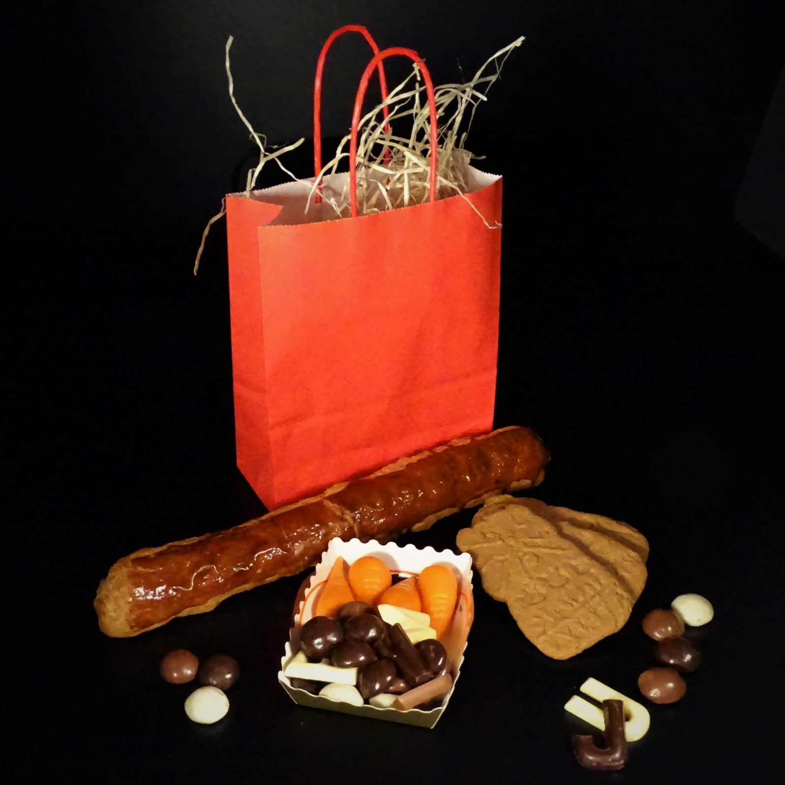 Sinterklaaspakket met speculaasstaaf, chocoladeletter, kruidnoten en snoep in een rode cadeautas